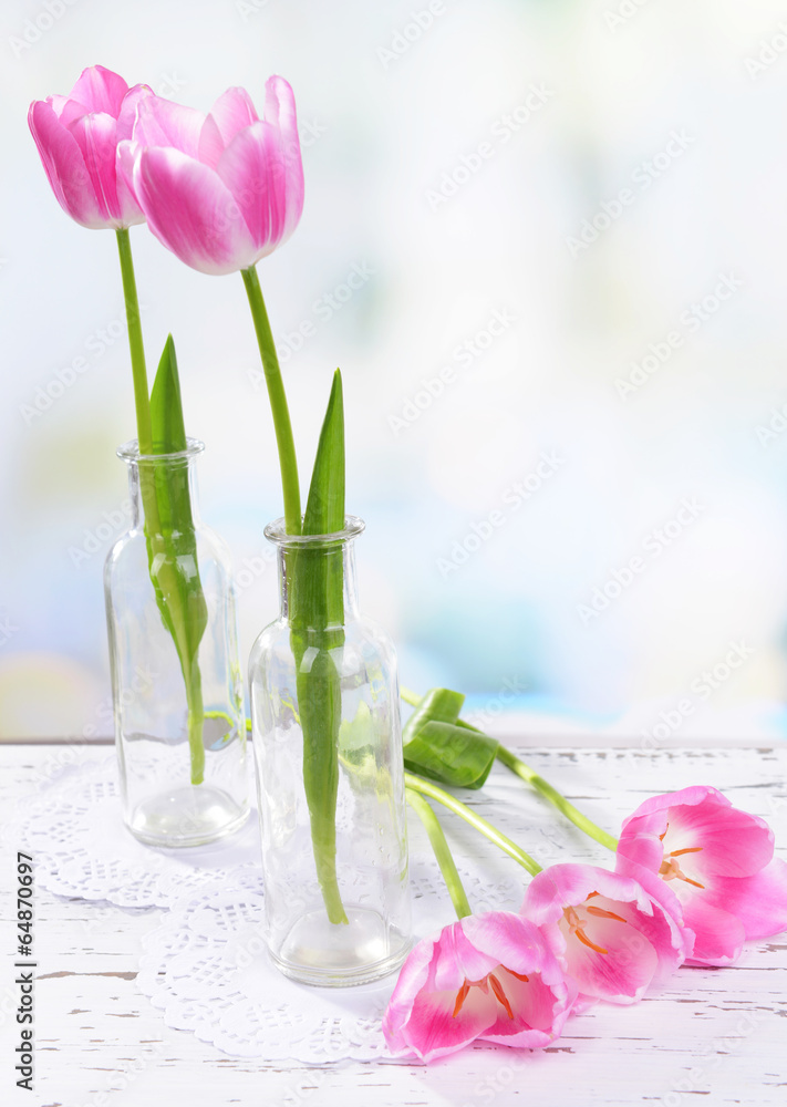 Beautiful tulips in bucket in vase on table on light background