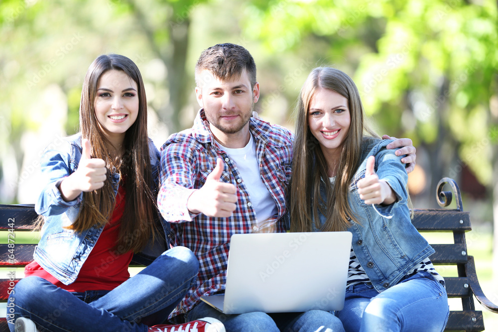 Happy students sitting in park
