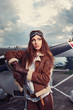 Portrait of young beautiful woman pilot in front of airplane.
