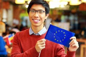 Sticker - Smiling asian boy in glasses holding flag of europe union