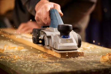 Elderly man planing a plank of wood