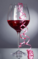 Glass of red wine and streamer after party on gray background