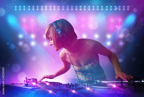 Board z aluminiowym obramowaniem Disc jockey miksująca muzykę na gramofonach na scenie ze światłami i