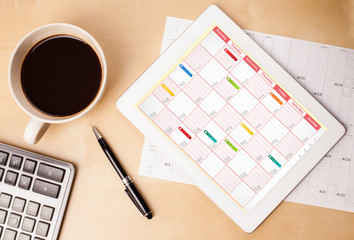 Wall Mural - tablet pc showing calendar on screen with a cup of coffee on a d