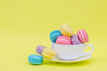 Sweet and colourful french macaroons in cup on retro-vintage bac