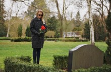 Sad Woman Grieves In A Cemetery Holding Roses