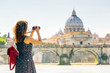 Young woman takes photo of St Peter's basilica, Vatican, Rome, Italy