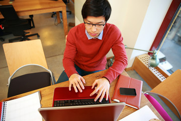 Canvas Print - Young asian man in glasses working on laptop in office