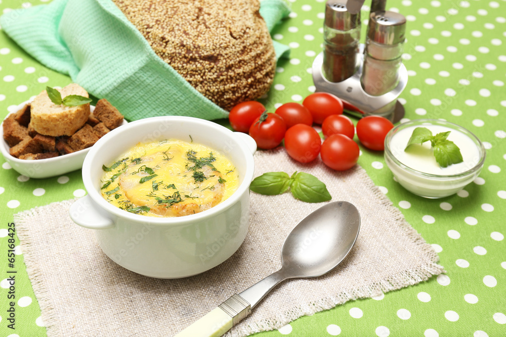 Tasty soup in saucepan on tablecloth, close up