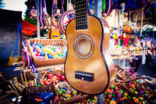 Small Guitar Hanging On The Stand For Sale During The Fair