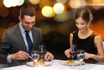 Wall Mural - smiling couple eating main course at restaurant