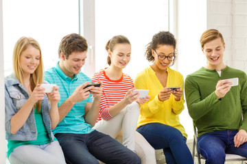 Wall Mural - smiling students with smartphone texting at school