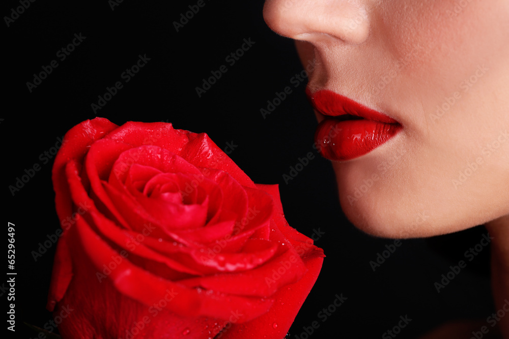 Girl with red lips and rose on dark background