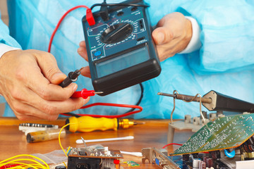 Wall Mural - Serviceman checks board of electronic device with multimeter