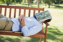 Man Sleeping On Park Bench With Newspaper Over Face