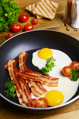 Poster - Scrambled eggs and bacon on frying pan on table close-up