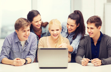 Wall Mural - smiling students looking at laptop at school