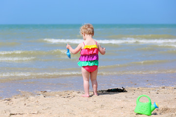 Cute little girl building sand castles on tropical beach