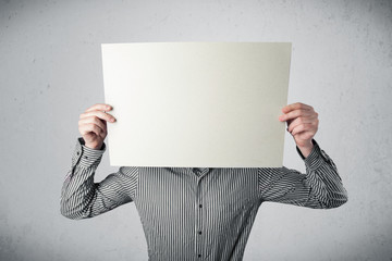 Businessman holding in front of his head a paper with copy space