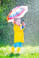 Wall Mural - Funny toddler with umbrella playing in the rain