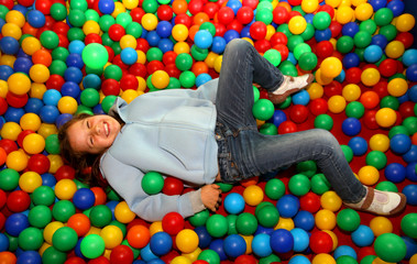 Wall Mural - nice little girl playing in the pool with colored plastic balls