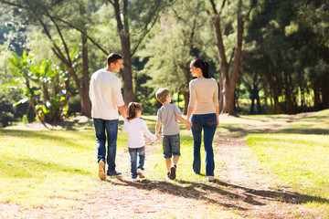 Wall Mural - rear view of young family walking in forest