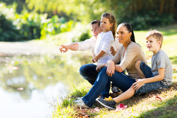 Wall Mural - young family sitting by lake