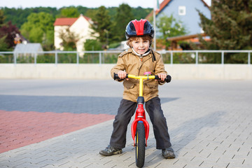 Wall Mural - Little toddler boy learning to ride on his first bike