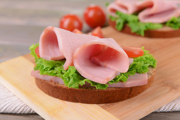 Wall Mural - Delicious sandwiches with lettuce and ham on table close-up