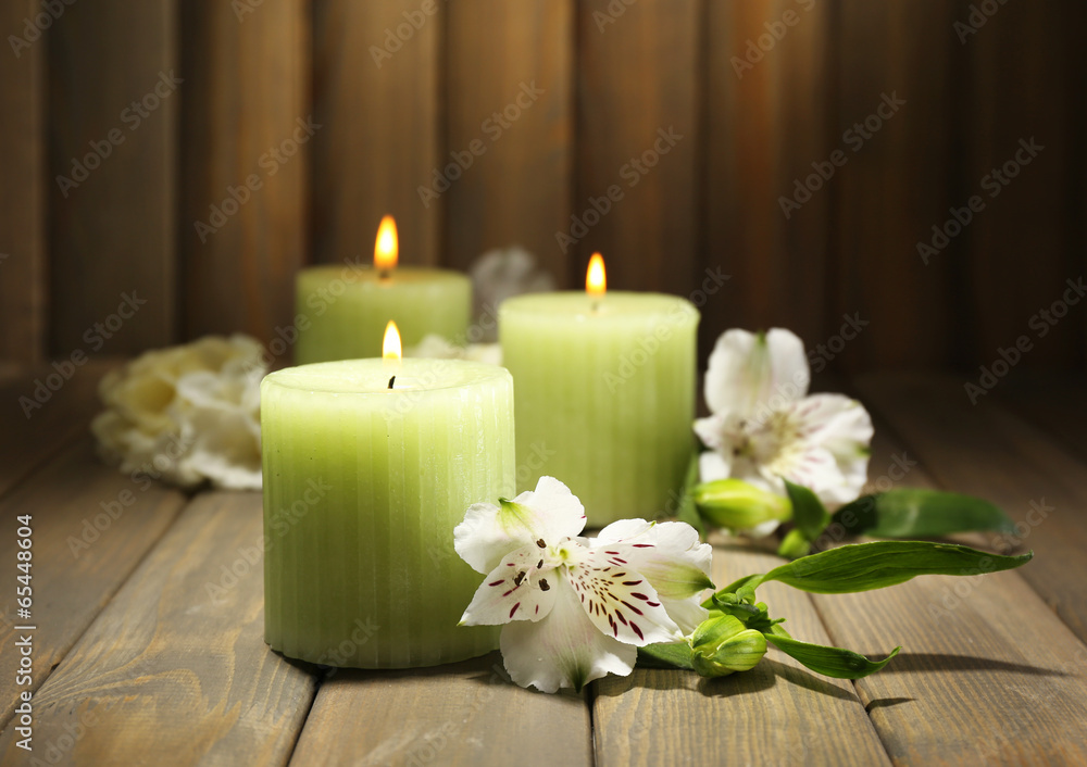 Beautiful candles with flowers on wooden background