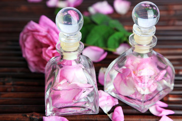 Wall Mural - Rose oil in bottles on bamboo mat background