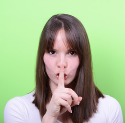 Portrait of girl with gesture for silence against green backgrou