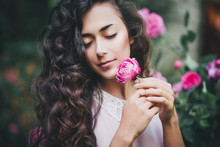 Young Woman Holding A Pink Rose In Her Hands In A Park