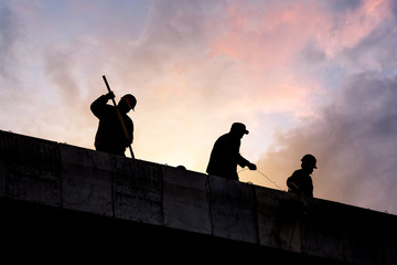 Construction workers silhouette in sunset