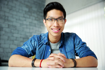 Sticker - Young happy asian man sitting at the table