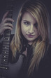 Beautiful blond girl holding black electric guitar