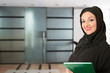 Arabic woman, standing in front of the office.