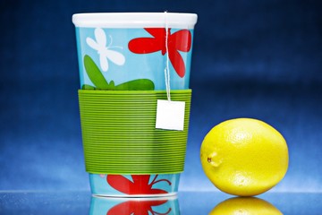 Tea cup with lemon,standing on the glass surface.