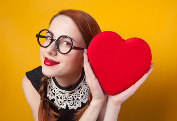 Wall Mural - Nerd redhead girl with heart shape on yellow backgorund.