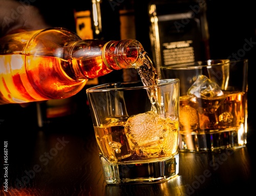 Fototapeta na wymiar barman pouring whiskey in front of whiskey glass and bottles