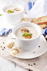 Mushroom soup in white pots, on napkin, on wooden background