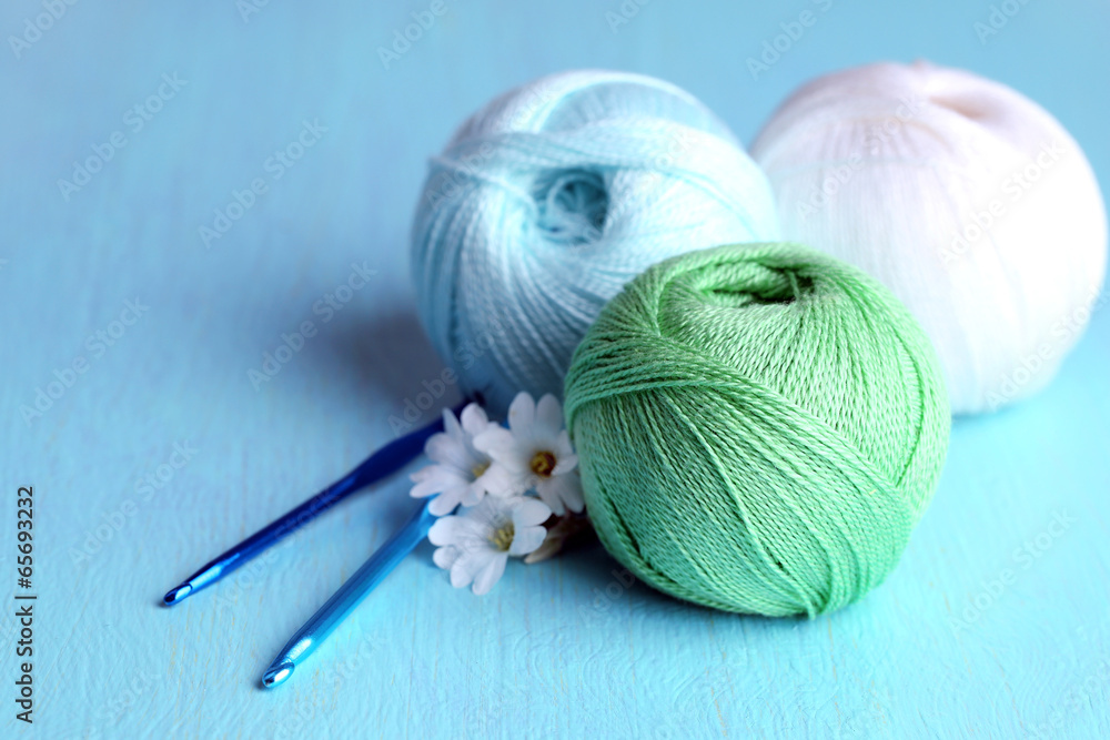Colorful clews and crochet hooks on wooden background