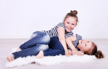 Beautiful small girls lying on floor on wall background