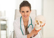 © Alliance - Portrait of happy medical doctor woman showing human skull