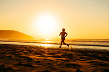 Female Athlete Running On Sunset At Beach