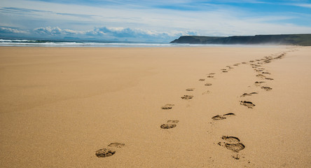 Footprints of hiking boots on the sand of a remote beach in Scot