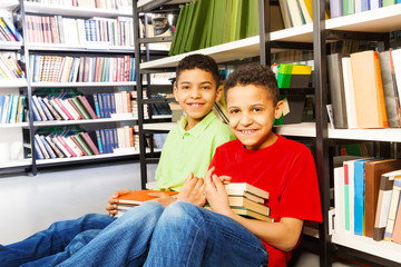 Two happy boys sitting on the floor in library