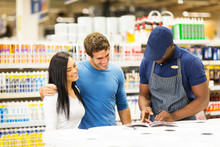 Young Couple Choosing Paint Color With Help Of Hardware Store Wo