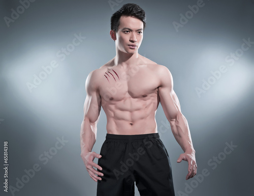 Plakat na papierze fotorealistycznym Umięśniony asian kung fu mężczyzna w pozie działania. 