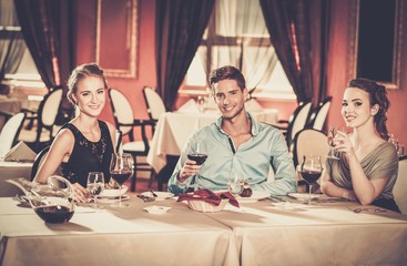 Wall Mural - Young friends with glasses of wine in a restaurant